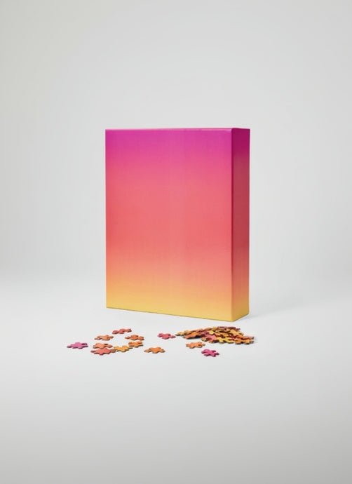 Gradient pink to yellow puzzle box with scattered puzzle pieces on a white background