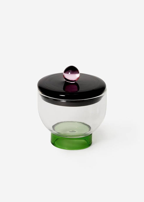 Glass container with a black lid and green base on a white background